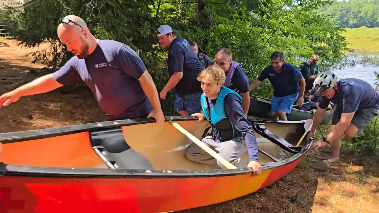Adventurelore participants working together to carry a canoe beside the lake