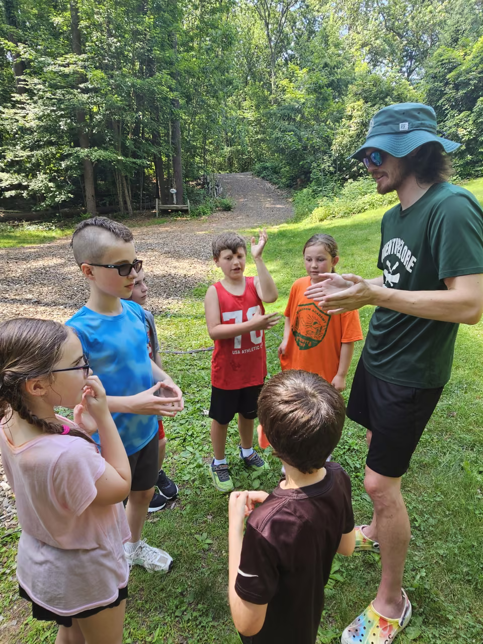 An Adventurelore staff member leading a shared activity with day campers outdoors