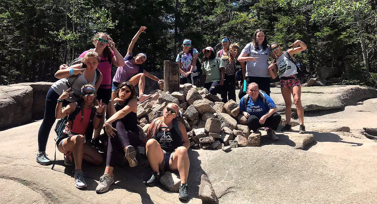 Acadia Girls campers together by a rocky shore