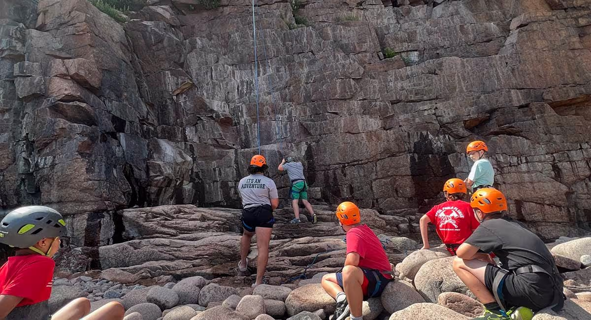 Junior campers exploring rocky terrain in helmets