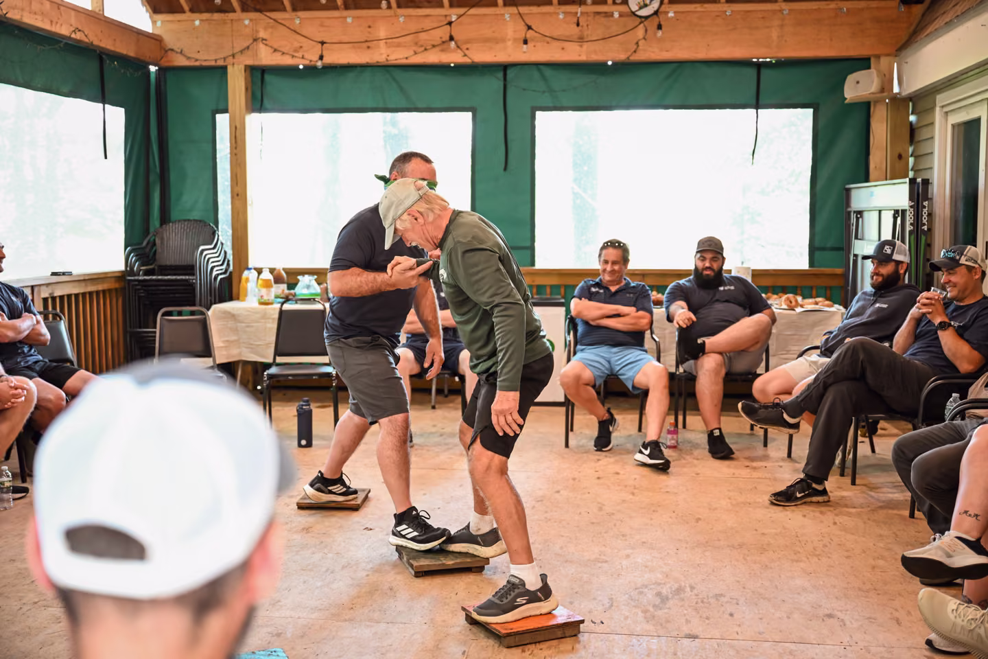 Adults taking part in a facilitated group challenge while teammates watch